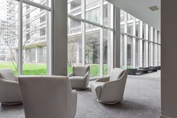 Armchairs next to panel of large windows at Optima Old Orchard Woods luxury apartments in Chicago Suburbs